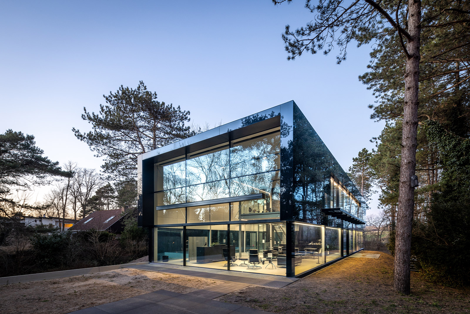 L’architecture épurée, presque futuriste, de ce parallélépipède de verre et de métal … contraste magnifiquement avec son environnement naturel dont les reflets sur ses façades vitrées paraissent vouloir l’absorber.